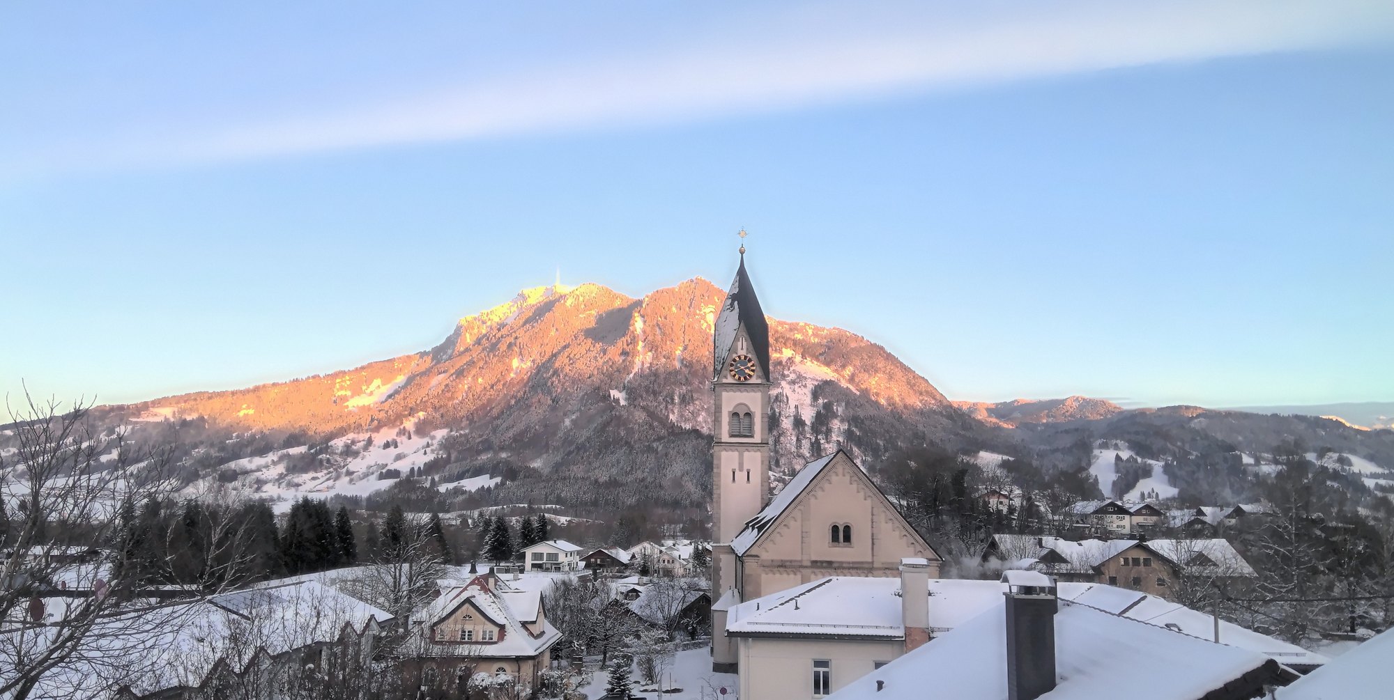 Blick vom Boutique House: Alpenglühen am Grünten über der Kirche von Blaichach